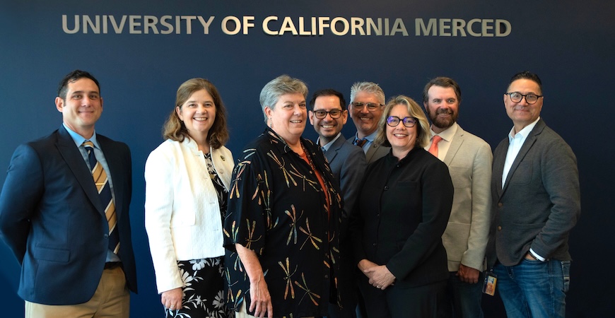 UC Merced and Almond Board officials are pictured underneath letters that spell out "University of California Merced"