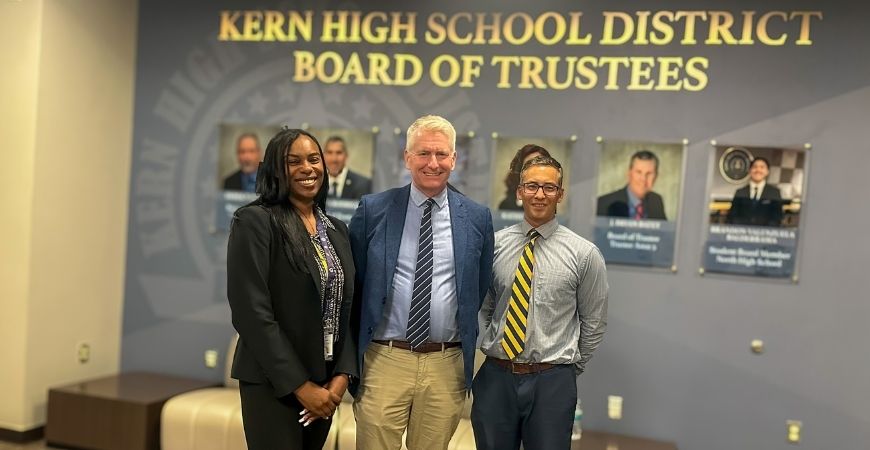 UC Merced and Kern High School District leaders pose in the lobby of the board room at a meeting.