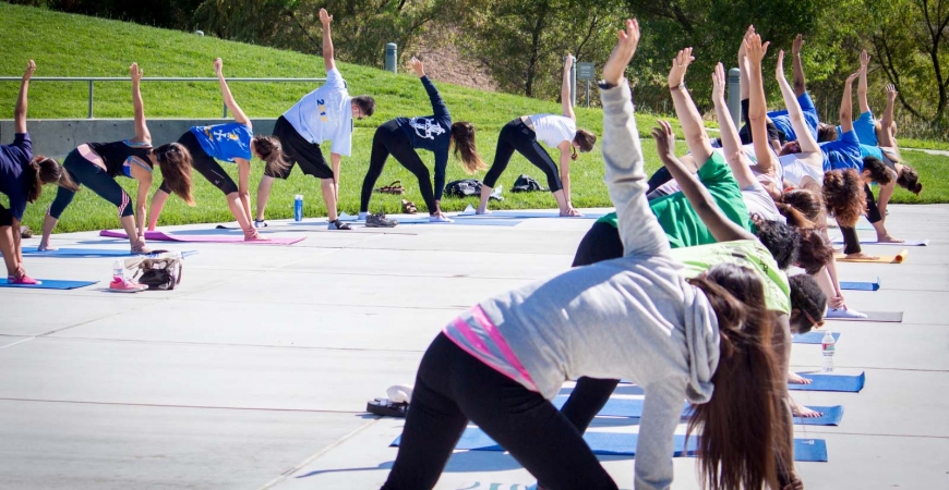 A large group practices yoga outdoors at UC Merced.