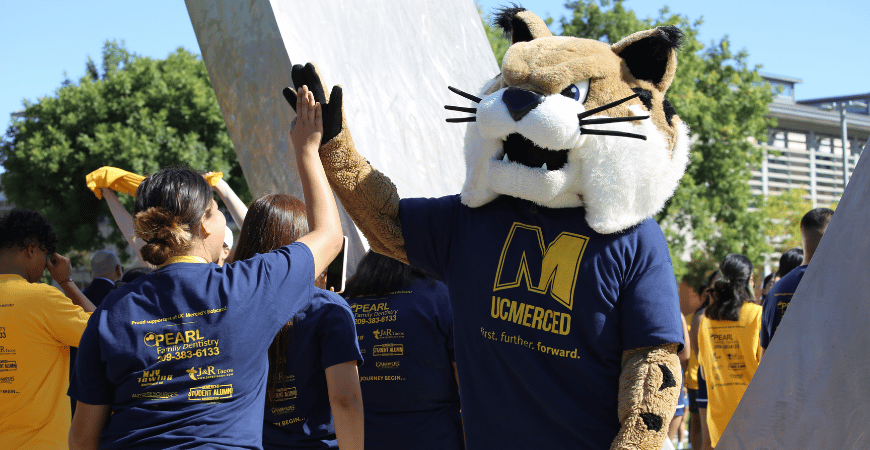 Rufus Bobcat high fives with a student