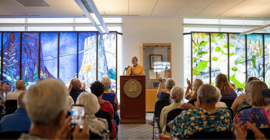Mural artist William Paulson addresses event attendees behind a podium