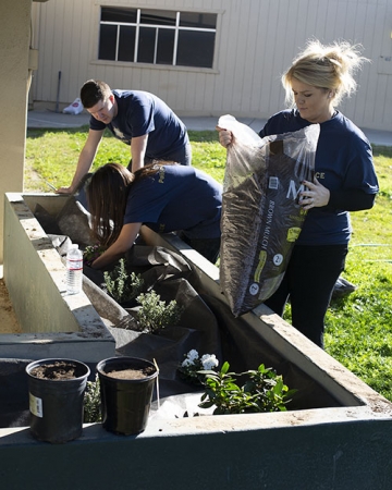 UC Merced Police Sgt. Kari Gomes prepares to spread soil among freshly planted flowers at the local elementary school.