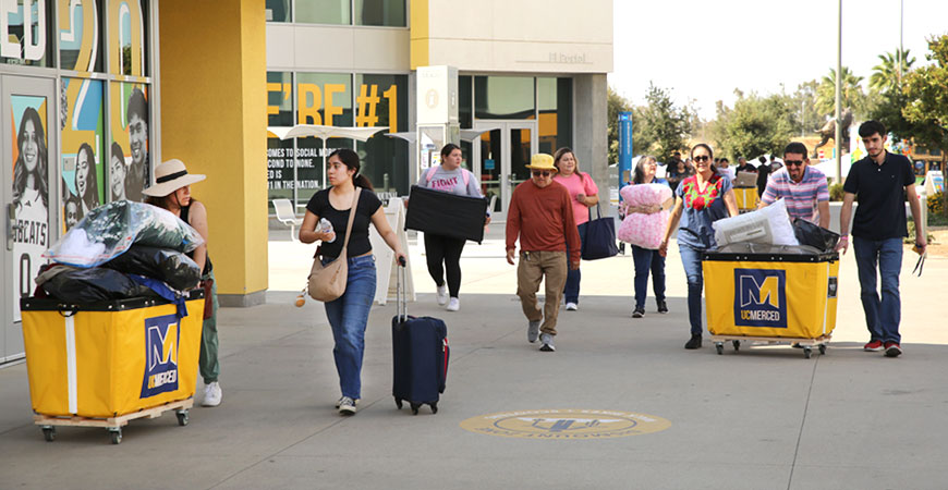 Parents and student push carts with belongings during move-in day