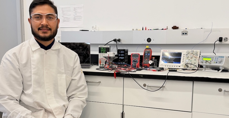 Postdoctoral researcher Dilawer Ali is seen sitting next to lab equipment at UC Merced.