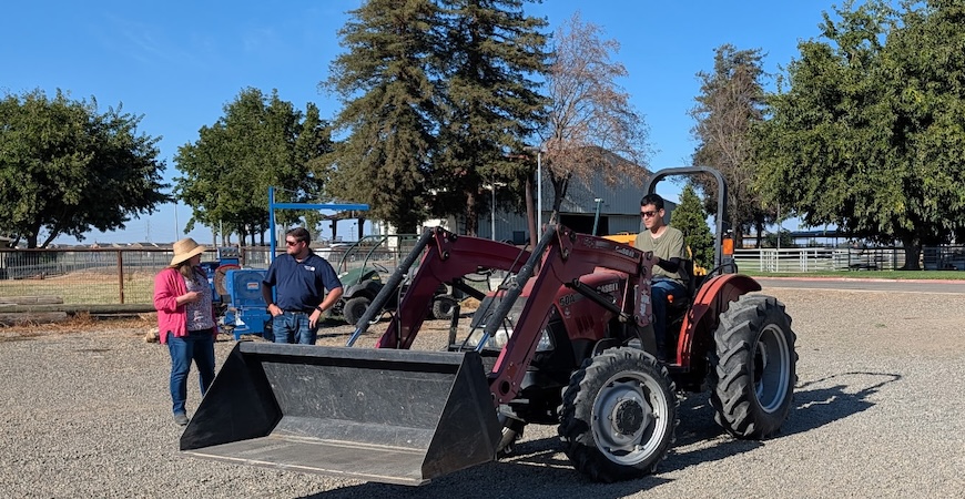 Tractor operator classes are part of the training. Here, a student operates a tractor while instructors provide guidance.