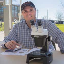 David Gravano sitting next to microscope