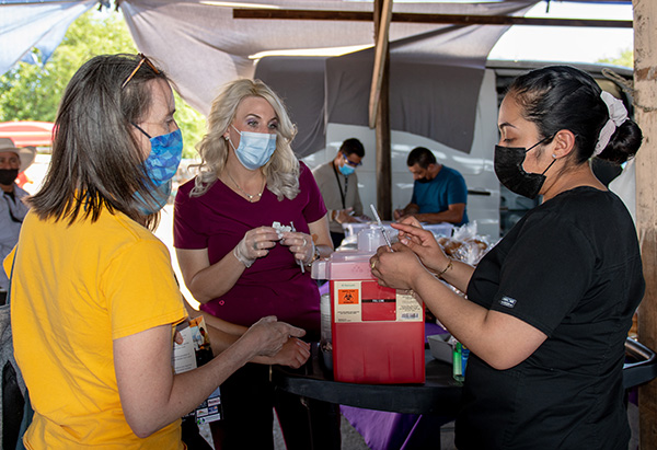 UC Merced Public Health Professor Nancy Burke speaks with nurses from Golden Valley Health Centers during a COVID-19 vaccine event.