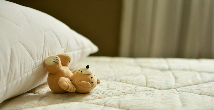 Una imagen muestra un peluche sobre una cama.