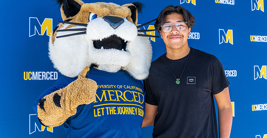 UC Merced's mascot Rufus and a student pose for a photo.