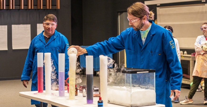 Two men in safety garments and goggles conduct an experiment at UC Merced.