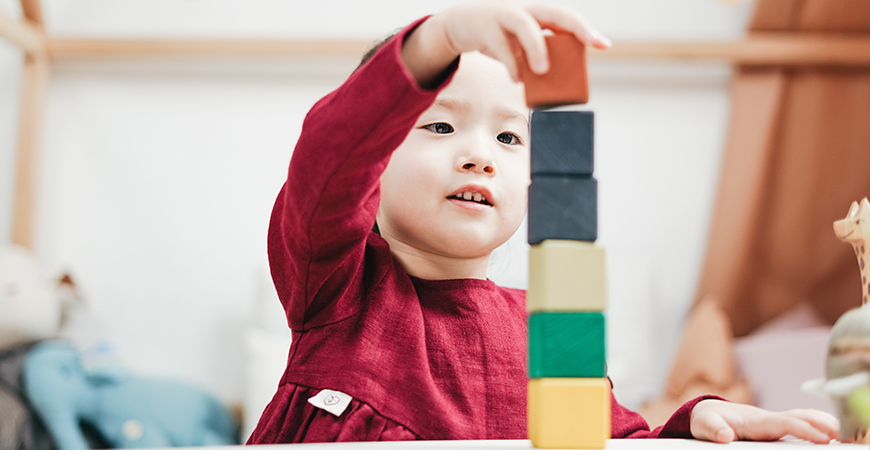 A child plays with blocks in a classroom.