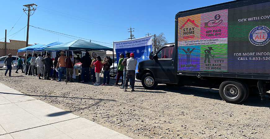People line up to receive information about COVID-19 and workers' rights at an event in Huron, California.