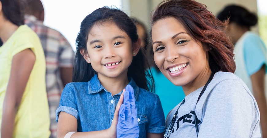 A child and a health worker are shown giving a high five.