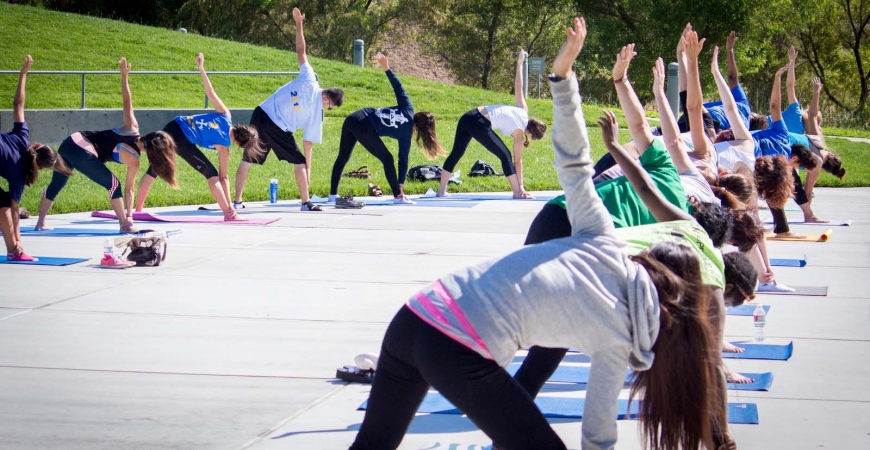 A large group practices yoga outdoors at UC Merced. 