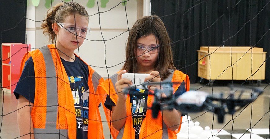 Two kids flying a drone at the Mobile Maker Space at the Merced County Fair.