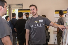 A student discusses his research poster during the MACES event.