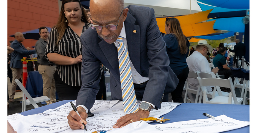 UC President Michael Drake signs a white coat to celebrate an important milestone for UC Merced's Medical Education Building.