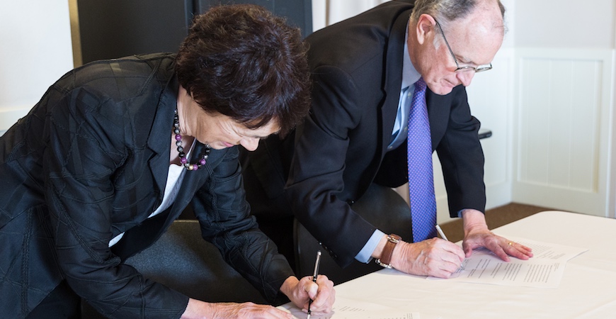 Chancellor Dorothy Leland and Berkeley Lab Director Michael Witherell sign MOU agreement on a white table.