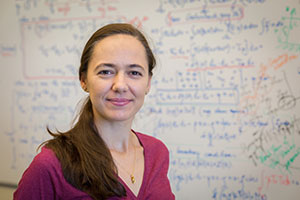 Professor Noemi Petra uses a huge equation, behind her, to address inverse problems.
