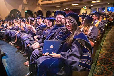 Graduate students pose after receiving their diploma.