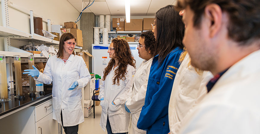 Professor Rebecca Ryals, left, talks to students in her lab.