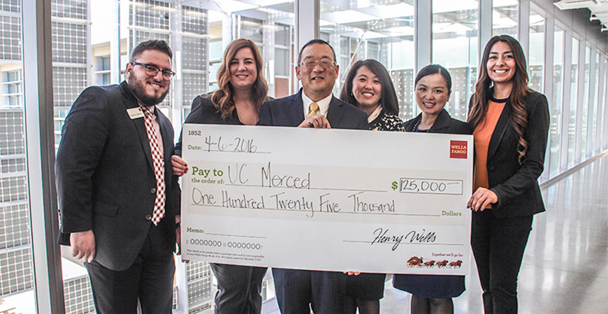 6 adults in business suits holding a large honorary check in the amount of $125,000