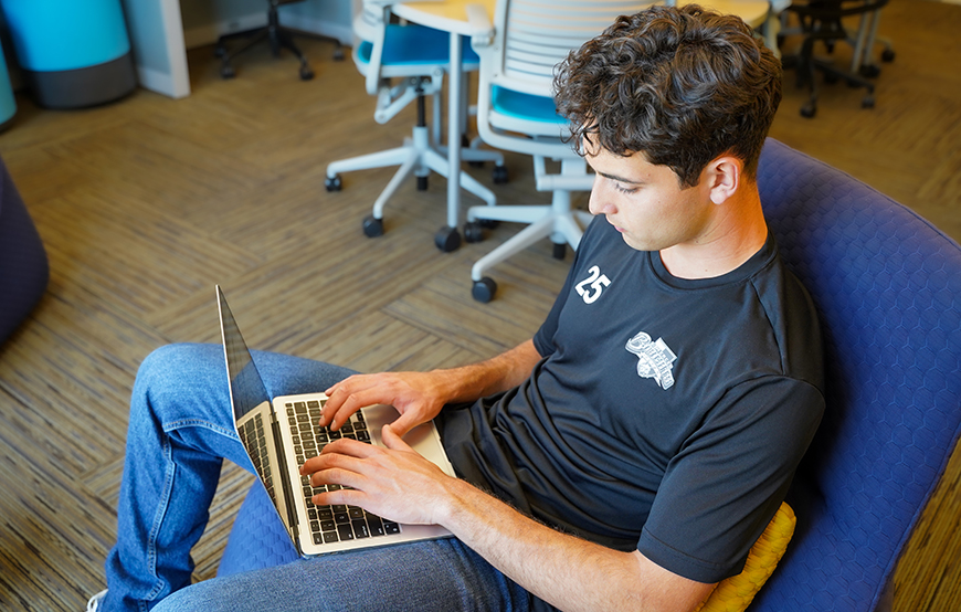 UC Merced student Edwin Casillas sits while typing on a laptop.