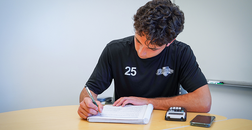 UC Merced student Edwin Casillas sits while writing in a notebook.