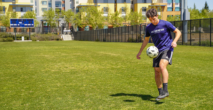 UC Merced student Edwin Casillas plays soccer on a field.
