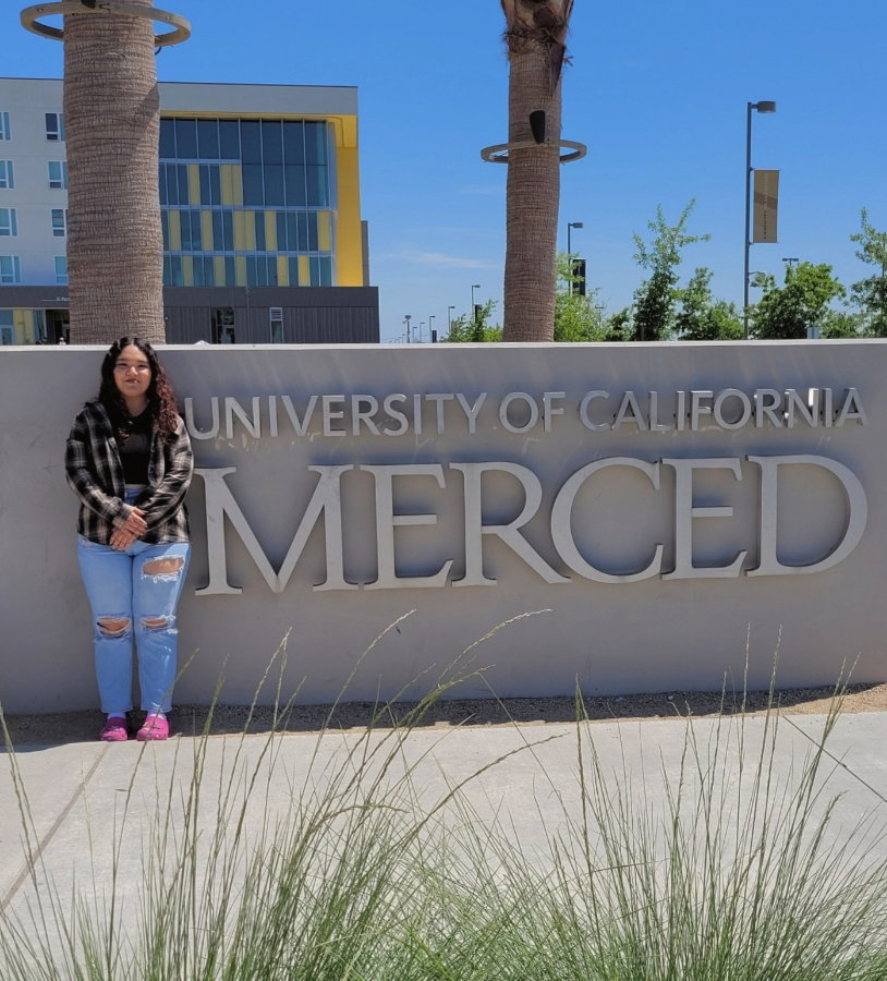 Analee Muñoz Luna poses for a photo in front of a sign at UC Merced.