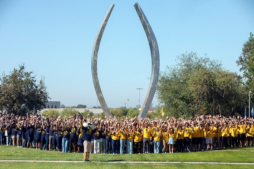A crowd poses in front of the Beginnings sculpture at UC Merced.