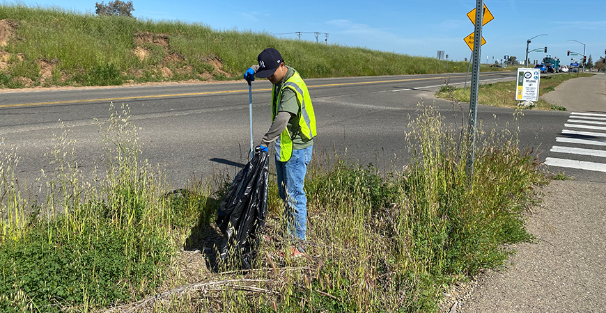 A UC Merced student helps to clean up the bike path along Lake Road.